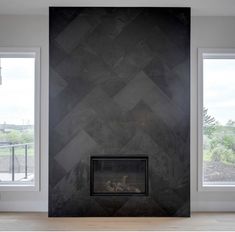 an empty room with two windows and a fireplace in the center, surrounded by black marble