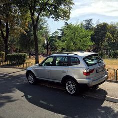 a silver car is parked on the side of the road in front of some trees