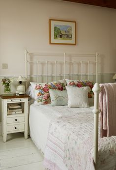 a white bed topped with lots of pillows next to a night stand and nightstands