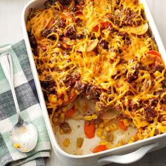 a casserole dish with meat, cheese and veggies in it next to a spoon