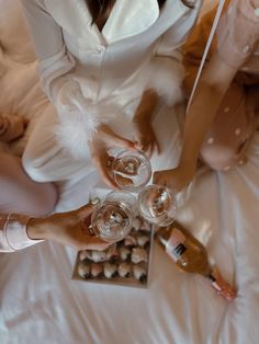 two women sitting on a bed holding wine glasses