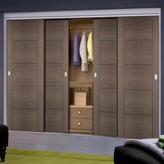 an open closet with clothes hanging on the doors and drawers in it, next to a green rug