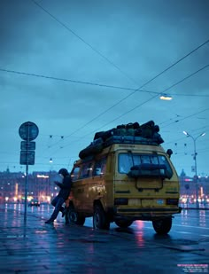 a yellow van with luggage on top parked in the rain