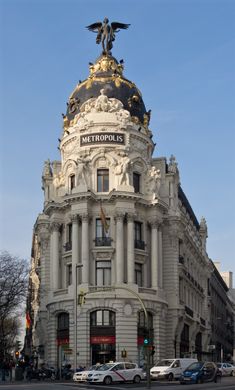 an ornate building on the corner of a street with cars parked in front of it