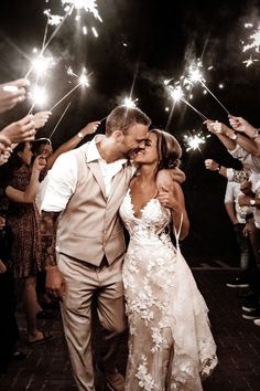 a newly married couple kissing while surrounded by sparklers