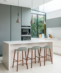 three stools sit at the center of a kitchen island with an oven in the background