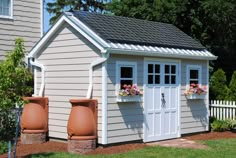 a small shed with two large flower pots in front of it