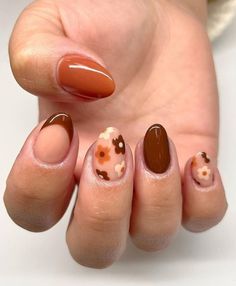 a woman's hand with some brown and white nail polishes on her nails