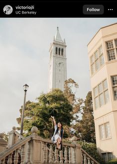 a woman standing on top of a set of stairs next to a tall clock tower