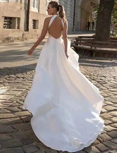 a woman is walking down the street in a white wedding dress with an open back