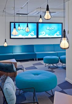 an office lobby with blue couches and two television screens