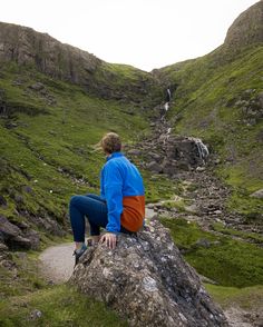 a person sitting on top of a large rock