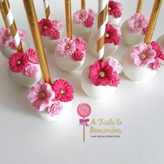 pink and gold flowers are on top of white balls with candy canes in them