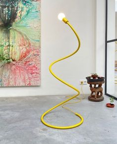 a yellow lamp sitting on top of a floor next to a painting