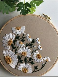 white daisies are embroidered onto an embroidery hoop