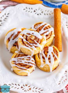 cinnamon rolls on a plate with icing drizzled over them and cinnamon sticks