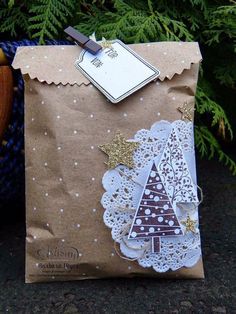 a brown paper bag with white doily and a christmas tree on it, sitting next to a potted plant