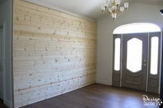 an empty room with wood paneling on the walls and two double doors leading to another room