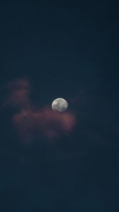 the moon is shining brightly in the dark night sky, with pink clouds behind it