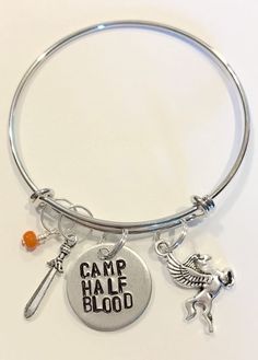 "Order by December 15th for delivery in time for Christmas. I am not responsible for any delays caused by USPS Inspired by the popular book series, this bracelet features charms of a pegasus and a sword with an orange bead. A 1\" hand-stamped disc says \"Camp Half Blood\" and hangs on an 18\" chain. Due to monitor settings, colors may vary from what you see on your screen. Since each item is stamped by hand, the exact spacing of the letters may be slightly different than what is pictured. No two pieces are exactly the same! All orders are shipped as soon as possible. Please understand that since everything in this shop is hand-made by one person, it make take up to 7 days. If you need your item sooner, please feel free to contact me and I'll see what I can do. All items are made with love Percy Jackson Bracelet, Percy Jackson Jewelry, Percy Jackson Heroes Of Olympus, Popular Book Series, Fandom Jewelry, Blue Cookies, Percy Jackson Cast, Trials Of Apollo, Percy Jackson Art