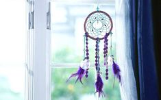 a purple dream catcher hanging on a window sill next to a blue drapes