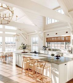 an open kitchen and dining area with white walls, wood floors and vaulted ceilinging