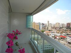 a balcony with pink flowers on it and the city in the background from an apartment building