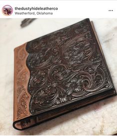 a brown leather journal sitting on top of a white countertop next to a pen