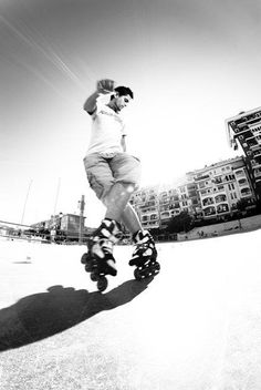 a man riding a skateboard down the side of a road next to tall buildings