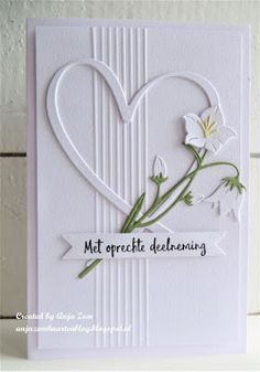 a white card with some flowers in the shape of a heart and words on it