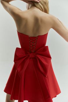 Introducing the Emily Dress with Bow: a stunning mini satin dress in a vibrant red color, designed to make a bold statement. This eye-catching dress features a dramatic maxi bow at the lower back, perfect for girls who love to stand out and make an impression. The Emily Dress is not only striking in design but also offers a perfect fit with adjustable lacing at the back. This ensures that you feel comfortable and confident throughout any special event. The vibrant red hue enhances its sophistica Black Elopement Dress, Black Elopement, Mini Satin Dress, Dress With Big Bow, Custom Wardrobe, Red Bow Dress, Bday Dress, Vestido Pink, Jade Dress