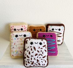 four crocheted cell phones sitting on top of a white table next to each other