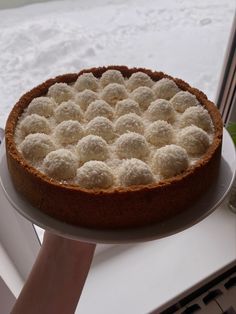 a person holding a cake on a plate with white icing and balls in the middle