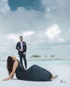 a woman laying on the ground next to a man in a tuxedo standing behind her