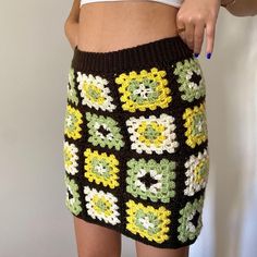 a woman is wearing a crocheted skirt and pointing to the side