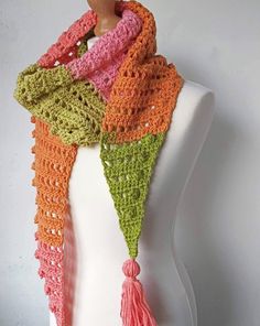 a crocheted scarf with tassels on top of a mannequin