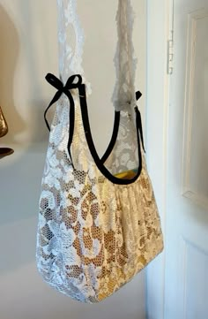 a white purse hanging from a hook on a door handle with lace and ribbon around it