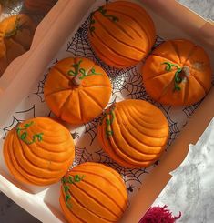 four orange pumpkins in a box on a table