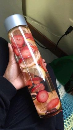 a person holding a water bottle with strawberries in it