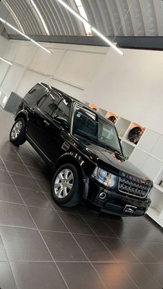 a black land rover is parked in a showroom