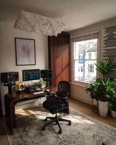 a room with a desk, chair and computer on top of the table in front of a window