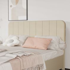 a bed with white sheets and pink pillows