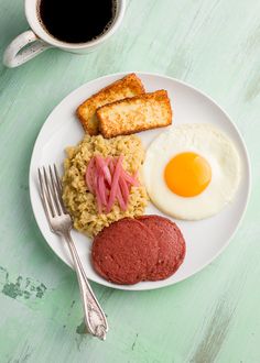 a white plate topped with meat, rice and an egg next to two slices of toast