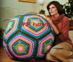 a woman sitting on the floor with a large crocheted ball in front of her