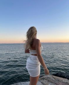 a woman standing on top of a rock next to the ocean