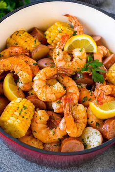 a bowl filled with shrimp and corn on the cob, garnished with parsley