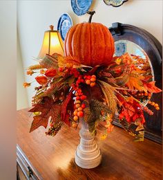 an arrangement of leaves, berries and pumpkins on a table in front of a mirror