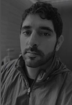 a black and white photo of a man in a jacket looking at the camera with a serious look on his face