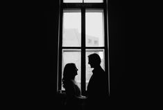 a man and woman standing in front of a window