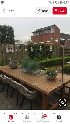 a wooden table sitting on top of a patio next to a fence and some plants